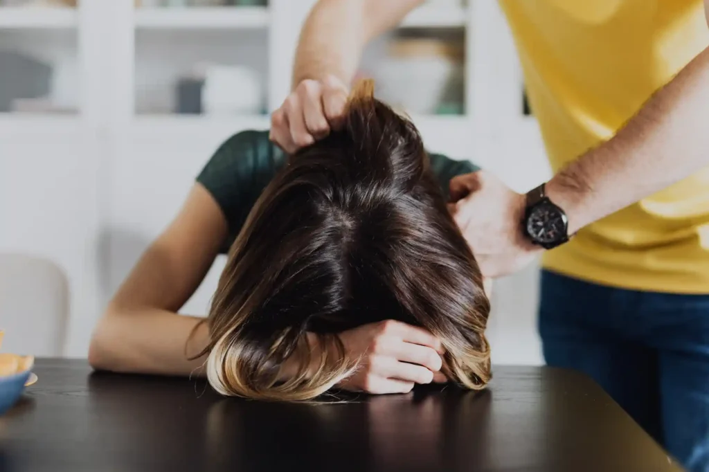 A woman having her head held down by a man.