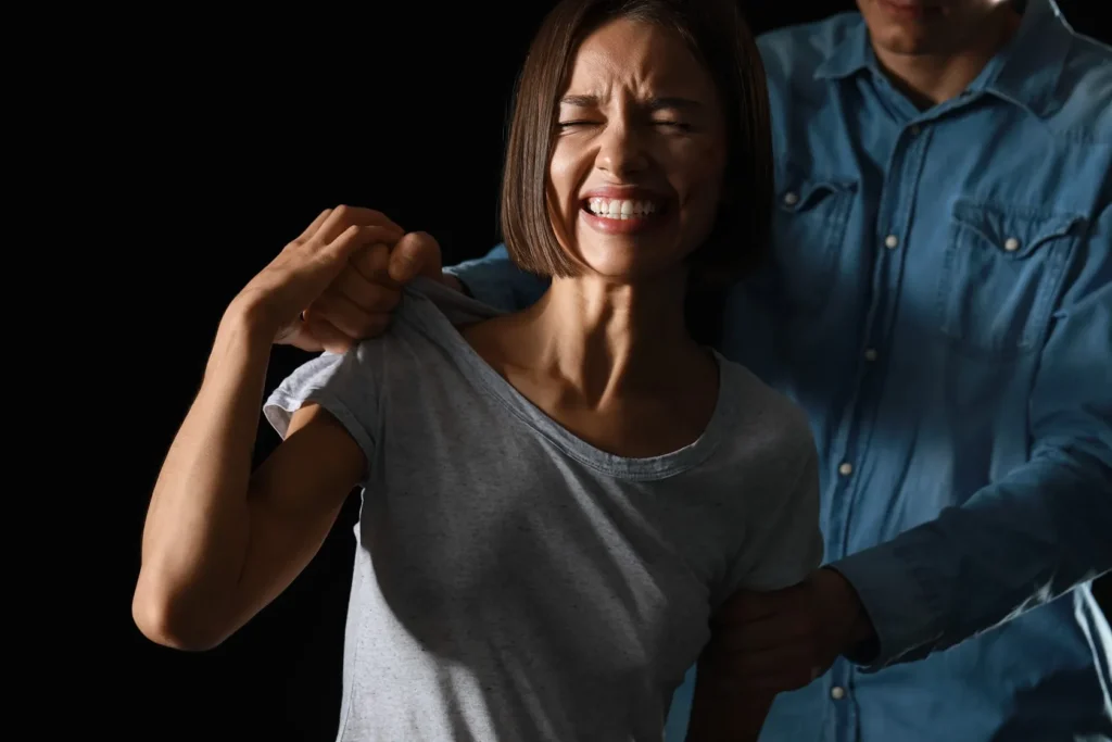 A woman being grabbed by a man and her face showing pain from the domestic violence.